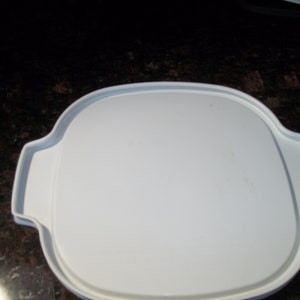 May include: A white, oval-shaped serving dish with a lid. The dish has a smooth, clean surface and two handles on either side. The lid fits snugly on top, creating a complete and functional piece for serving food.