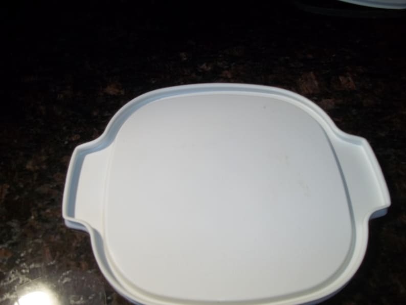 May include: A white, oval-shaped serving dish with a lid. The dish has a smooth, clean surface and two handles on either side. The lid fits snugly on top, creating a complete and functional piece for serving food.