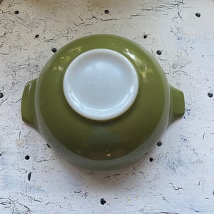 May include: A green Pyrex mixing bowl with two handles. The bowl has a white interior and the Pyrex logo is visible on the bottom.