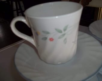 May include: A white teacup with a floral design and a matching saucer. The cup has a handle and the saucer has a blue rim.
