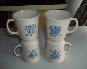 May include: Set of four white ceramic mugs with blue and green floral designs. Each mug features a basket of flowers with a checkered pattern.