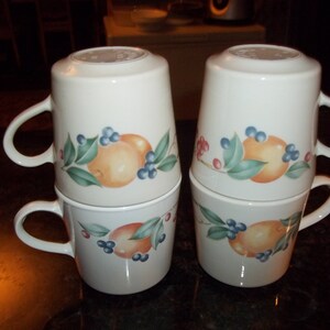 Puede incluir: Juego de cuatro tazas de cer&aacute;mica blanca con un dise&ntilde;o de frutas y flores. Cada taza presenta una fruta diferente, incluyendo naranjas, limones y limas. Las tazas tienen un fondo blanco con un dise&ntilde;o verde, amarillo y azul.