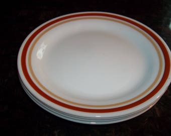 May include: A set of three white ceramic dessert plates with a brown and red rim.