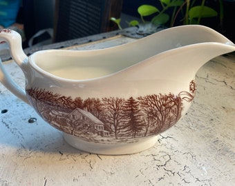 Pode incluir: Molho de cerâmica branca com um design de cena de inverno marrom e branco. A cena apresenta uma casa, árvores e neve.