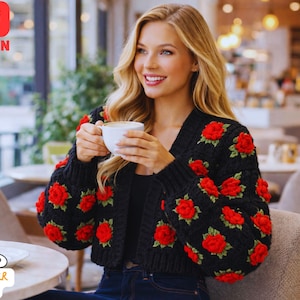 May include: A black crochet cardigan decorated with red rose motifs. The cropped sweater has long sleeves and a V-neck. The image also includes the text "PDF PATTERN" and a logo that says "CROCHETER KITTY B".