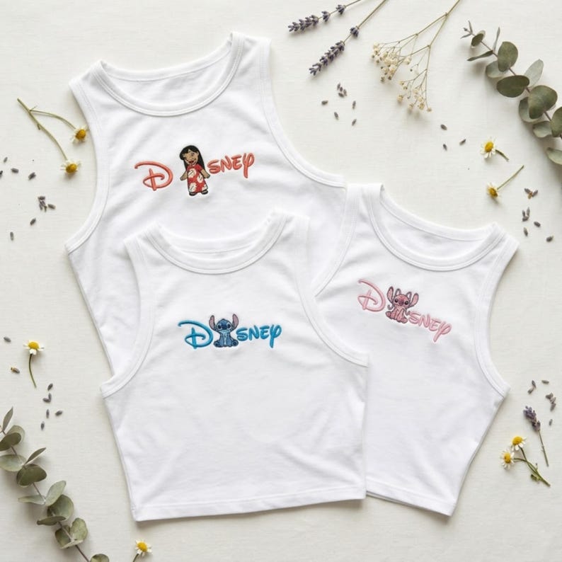 May include: Three white tank tops with Disney character embroidery. One top features Lilo, another Stitch, and the third Stitch. The Disney logo is embroidered in coordinating colors. The tops are sleeveless with a round neckline.