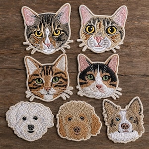 May include: A collection of seven embroidered animal patches featuring four cat faces with various tabby and calico markings, a white fluffy dog face, a golden curly-haired dog face, and a brown and white dog face with one blue eye.