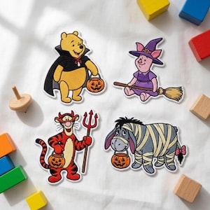 May include: Four embroidered patches featuring Winnie the Pooh characters in Halloween costumes: Pooh as a vampire with a pumpkin bucket, Piglet as a witch on a broom, Tigger as a devil with a trident and pumpkin bucket, and Eeyore as a mummy.