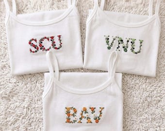 Canotta personalizzata con ricamo floreale e lettera dell'università, maglietta per bambini con tema universitario, maglietta universitaria con fiori, regalo per confraternita universitaria, regalo per lei