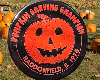 May include: A black and orange pumpkin carving champion award with the text "Pumpkin Carving Champion Haddonfield, IL 1978".