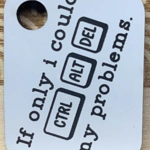 Könnte beinhalten: Ein weißer, rechteckiger Schlüsselanhänger mit abgerundeten Ecken. Der Schlüsselanhänger hat oben ein Loch und zeigt den Text "If only I could CTRL ALT DEL my problems." in Schwarz sowie die Tasten CTRL, ALT und DEL.