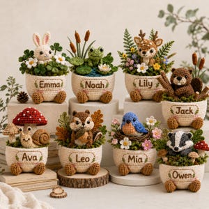 May include: A collection of eight crocheted animal planters, each featuring a unique creature like a rabbit, frog, deer, beaver, snail, squirrel, bluebird, or badger. Each cream-colored pot is personalized with a name and small crocheted feet.