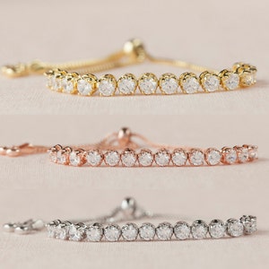 May include: Three adjustable bracelets with a row of clear cubic zirconia stones. The bracelets are available in gold, rose gold, and silver.