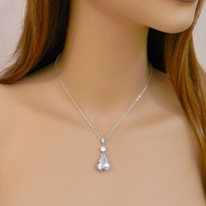May include: A silver necklace with a teardrop-shaped crystal pendant. The pendant has a smaller crystal accent above it.