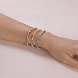 May include: Three delicate bracelets with a row of pear-shaped clear stones set in gold, rose gold, and silver.