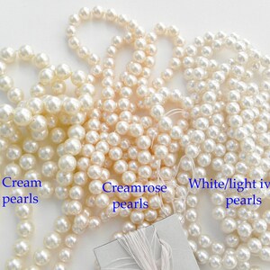 May include: Three strands of faux pearl beads in cream, creamrose, and white/light ivory colors. The beads are all the same size and are arranged in a loose pile.