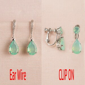 Op de afbeelding: Twee paar traanvormige oorbellen met groene stenen. Het ene paar heeft oorhaakjes en het andere paar heeft clip-sluitingen. De tekst "Ear Wire" en "CLIP ON" staat onder elk paar oorbellen.