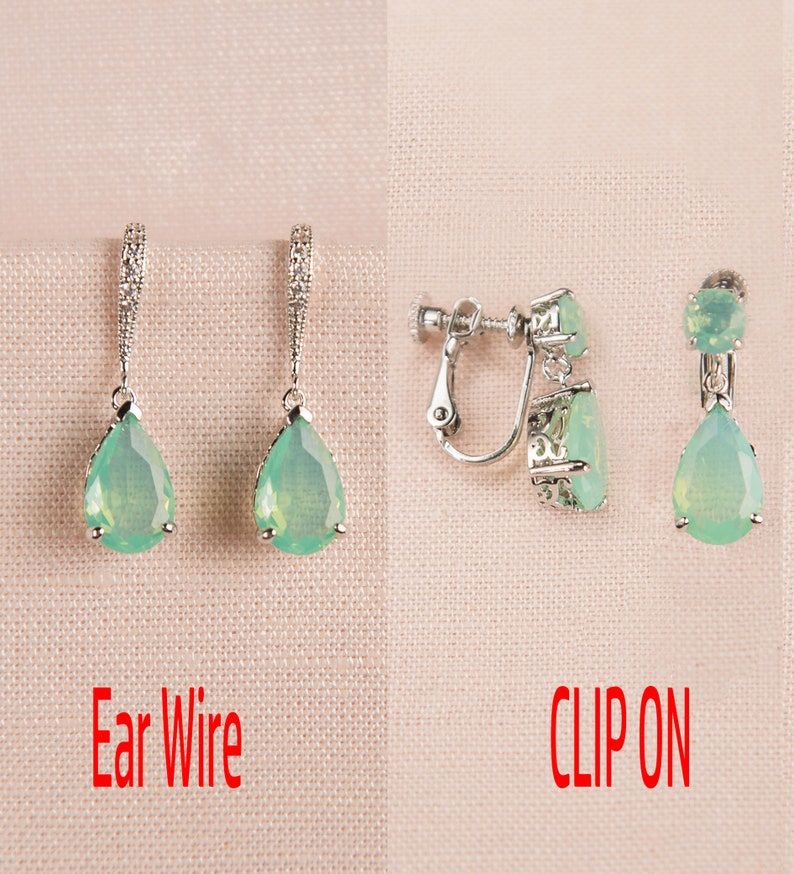 Op de afbeelding: Twee paar traanvormige oorbellen met groene stenen. Het ene paar heeft oorhaakjes en het andere paar heeft clip-sluitingen. De tekst "Ear Wire" en "CLIP ON" staat onder elk paar oorbellen.