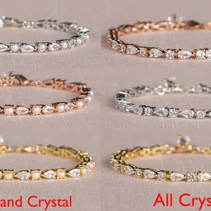May include: Four bracelets with a silver, rose gold, gold, and silver finish. Each bracelet features a row of pear-shaped crystals and pearls. The bottom two bracelets are labeled "Pearl and Crystal" and "All Crystals".