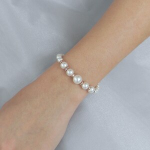 May include: A white pearl bracelet with small clear rhinestones on a rose gold chain.