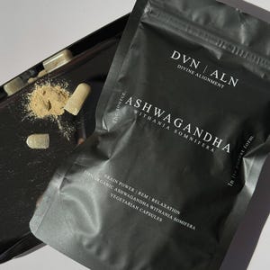 Puede incluir: Una bolsa negra de c&aacute;psulas de Ashwagandha con el texto "DVN ALN Divine Alignment" y "Ashwagandha Withania Somnifera". La bolsa tambi&eacute;n indica "Brain Power | REM | Relaxation" y "Vegetarian Capsules". El peso neto es de 200g.