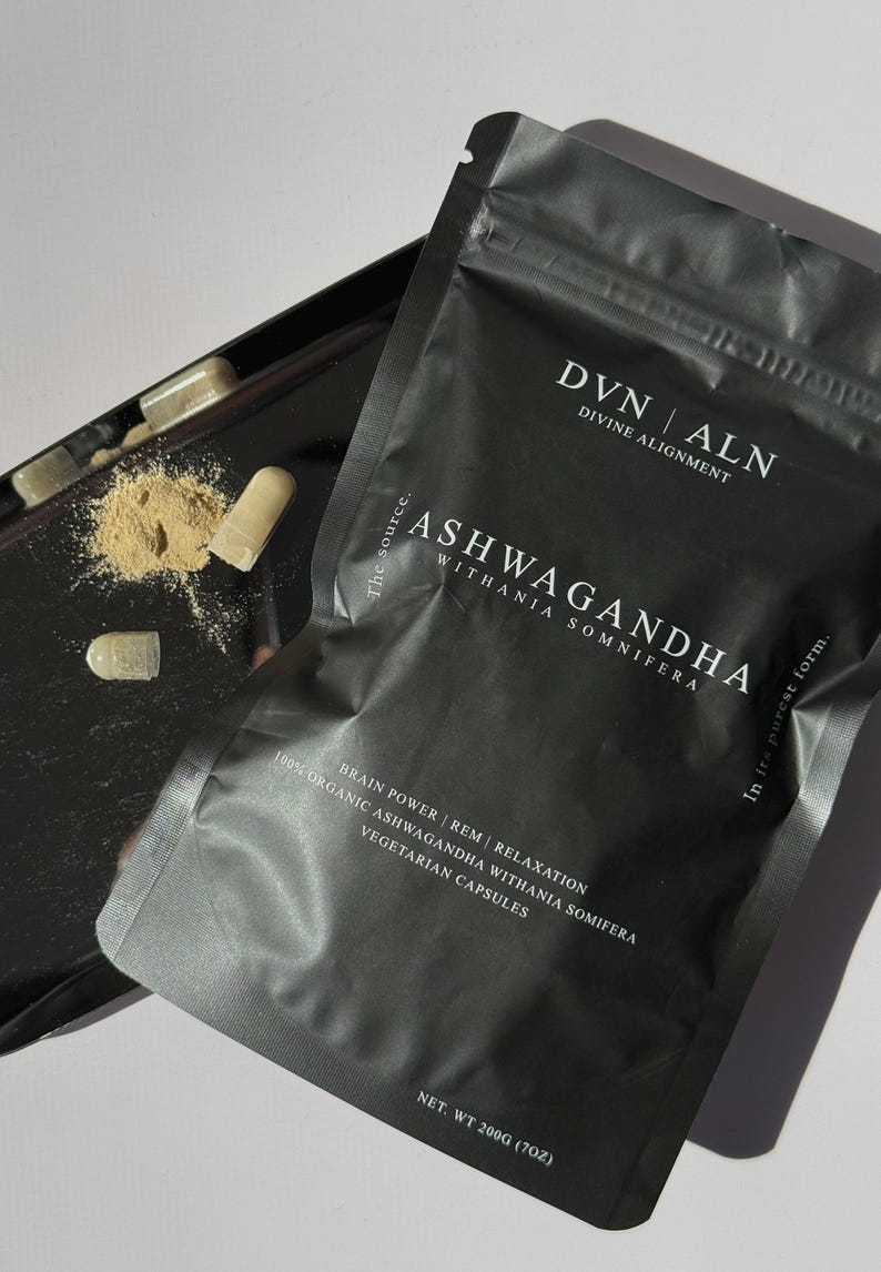 Puede incluir: Una bolsa negra de c&aacute;psulas de Ashwagandha con el texto "DVN ALN Divine Alignment" y "Ashwagandha Withania Somnifera". La bolsa tambi&eacute;n indica "Brain Power | REM | Relaxation" y "Vegetarian Capsules". El peso neto es de 200g.