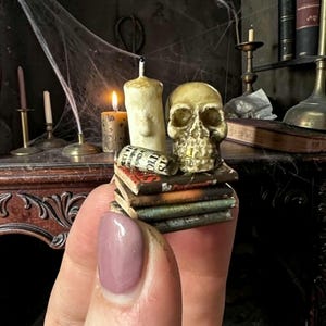 May include: A white ceramic mug with a black handle and the text "But First, Coffee" in a bold, black font. The mug is set against a neutral background, highlighting its simple design.