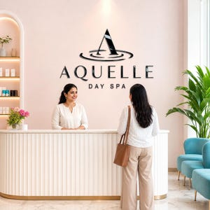 Può includere: Un'area reception con un bancone bianco scanalato e un'insegna a parete con il testo nero A QUELLE DAY SPA e un logo con una lettera A stilizzata. Un addetto in top bianco è dietro il bancone, mentre un visitatore in top bianco è davanti.