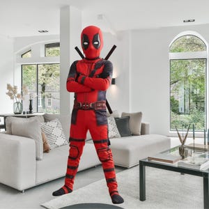 Può includere: Un costume integrale di Deadpool composto da una tuta rossa e nera con maschera abbinata, una cintura con fibbia centrale e due impugnature di spada nere che sporgono dalla schiena. La tuta presenta inserti neri sulle braccia e sulle gambe.