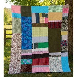 May include: A rectangular patchwork quilt featuring a variety of fabric squares and rectangles in diverse colors including blue, green, pink, brown, and yellow. The design incorporates floral, plaid, polka dot, and solid patterns stitched together.