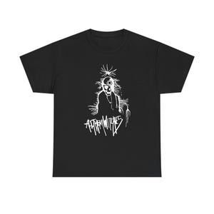 May include: Black t-shirt with a white graphic of a skull-like figure and the text "ANTHEM WITCHES". The design has a distressed look, suggesting a punk or alternative style. The t-shirt is likely made of cotton.