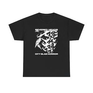 May include: Black t-shirt featuring a white graphic of a face composed of multiple eyes and the text "SEVERED HEADS" above and "CITY SLAB HORROR" below. The shirt is made of a soft, comfortable material.