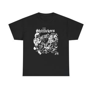May include: Black t-shirt with a white graphic featuring the text "Shitlickers Cracked Corp." above a detailed illustration of several figures. The design has a punk rock aesthetic.