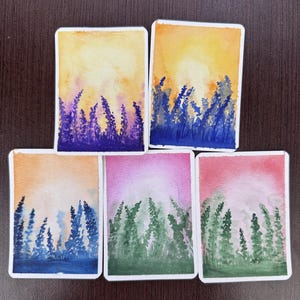 Op de afbeelding: Vijf rechthoekige aquarelschilderijen met verticale plantsilhouetten tegen gradiëntachtergronden. De kleuren omvatten geel, oranje, paars, blauw, roze en groen, die gestileerde velden of bossen onder heldere, zachte luchten weergeven.