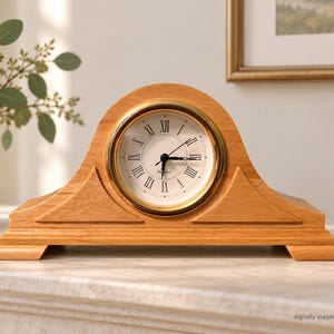 May include: A mantel clock with a light brown wooden arched frame and a circular face featuring black Roman numerals, a gold-toned bezel, and black hands. The clock has a stepped base and a white dial with the text "Waltham" printed on it.