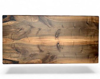 May include: A rectangular wooden table top with a natural wood grain pattern. The surface features a mix of dark brown and light brown tones, with visible knots and grain details. The table top is likely for a dining or coffee table.