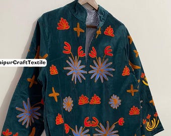 May include: A dark teal jacket with colorful floral embroidery. The jacket features a high collar, long sleeves, and a striped lining visible at the collar and cuffs. The embroidery includes blue, orange, and yellow floral designs. The text "JaipurCraftTextile" is visible on the jacket.