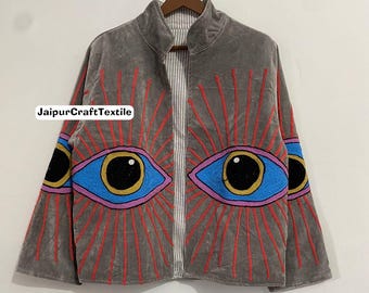 May include: Gray velvet jacket with embroidered eye design. The jacket features large blue eyes with black pupils and pink and yellow accents, radiating red lines. The jacket has a high collar and a striped lining. The text "JaipurCraftTextile" is visible.