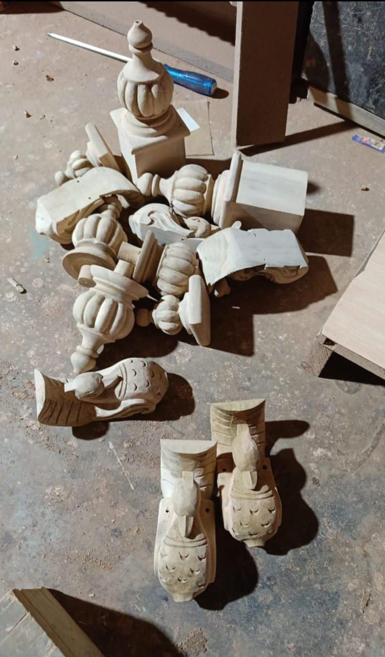 Puede incluir: Una colecci&oacute;n de tallas de madera sin terminar, de color claro, que incluyen pin&aacute;culos, elementos decorativos y detalles arquitect&oacute;nicos. Las piezas var&iacute;an en tama&ntilde;o y forma, algunas con dise&ntilde;os tallados intrincados. Los objetos est&aacute;n esparcidos sobre una superficie de hormig&oacute;n.