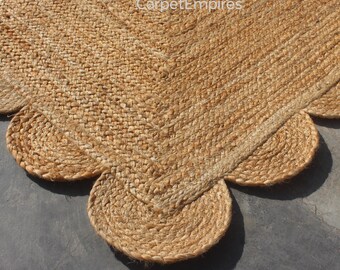 May include: A natural jute rug with a scalloped edge. The rug is a light brown color and has a woven texture. The scalloped edge adds a decorative touch to the rug's design. The rug is suitable for indoor use.