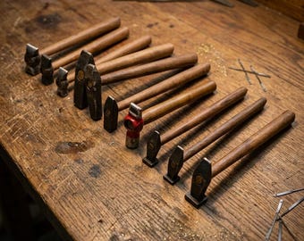 Juego de 10 martillos de hierro negro con mango de madera para forja de alta resistencia.