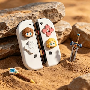 May include: Two white game controller attachments featuring raised silicone character icons including a brown-haired figure, a white owl, a blonde figure, and four pink circular shapes, accompanied by a small sword and a star-tipped wand.