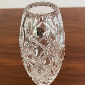 May include: Clear crystal vase with a diamond-cut pattern and a scalloped rim. The vase has a label that reads "MADE IN POLAND 24% LEAD CRYSTAL Hand cut."