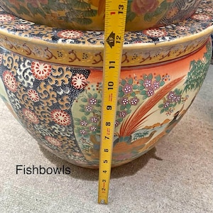 May include: A large, ornate fishbowl with a colorful floral and bird design. The bowl is primarily orange, blue, and gold, with intricate patterns. The text "Fishbowls" is visible. The bowl measures approximately 12 inches in height.
