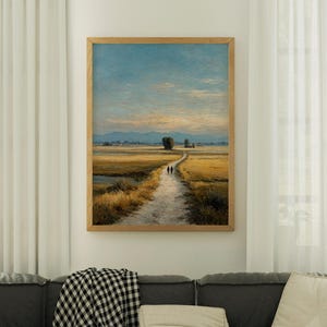 May include: A framed landscape painting depicting a path through a field under a blue sky. The artwork hangs above a dark gray sofa with cream-colored pillows and a black and white checkered throw. A wooden coffee table and glass bottle are in front.