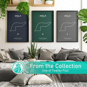 Op de afbeelding: Drie ingelijste Imola Italië circuitposters in marineblauw, groen en grijs. Elke poster toont een witte omtrek van het circuit, het woord "IMOLA" en de Italiaanse vlag. De posters worden weergegeven boven een grijze bank met sierkussens.