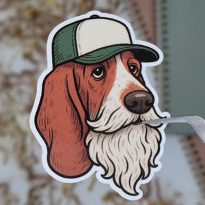 May include: A sticker featuring a cartoon basset hound wearing a green and white baseball cap and a long, white beard. The dog has brown and white fur and a sad expression.