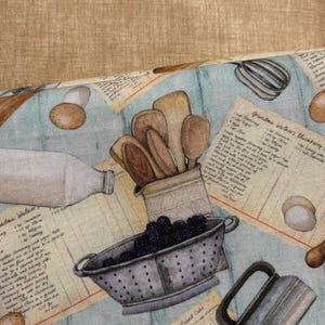 Może przedstawiać: Jasnoniebieska tkanina z motywem kuchni w stylu vintage. Wz&oacute;r zawiera ilustracje drewnianych łyżek, durszlaka z jeżynami, jajek, wałka do ciasta, butelki mleka i miksera ręcznego. Karty z przepisami są rozrzucone po tkaninie.