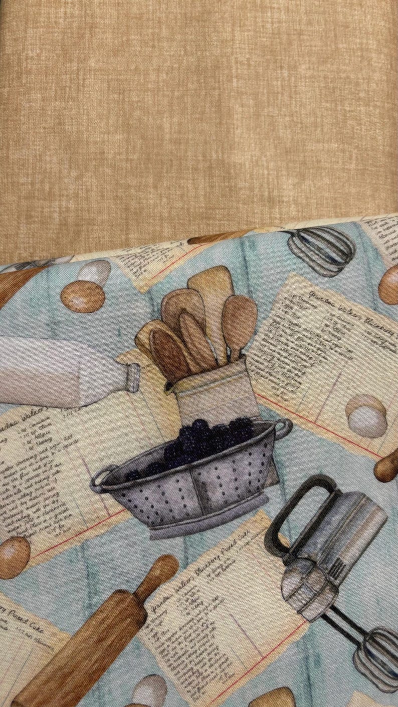Może przedstawiać: Jasnoniebieska tkanina z motywem kuchni w stylu vintage. Wz&oacute;r zawiera ilustracje drewnianych łyżek, durszlaka z jeżynami, jajek, wałka do ciasta, butelki mleka i miksera ręcznego. Karty z przepisami są rozrzucone po tkaninie.
