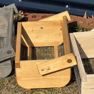 May include: Two wooden baskets with wire mesh bottoms and wooden handles. The baskets are made of natural wood and have a light brown stain. The baskets are sitting on a bed of brown grass.